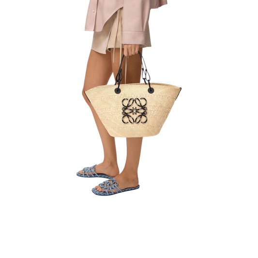 Via Manzoni Boutique model carrying a LOEWE Anagram medium basket bag in natural iraca palm with black calfskin trim.