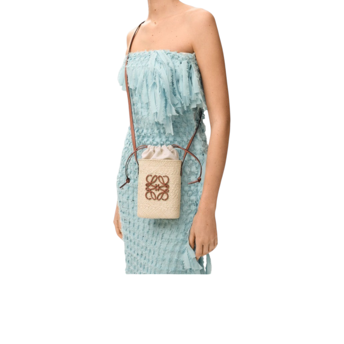 Via Manzoni Boutique LOEWE raffia bucket bag with tan leather Anagram logo and drawstring closure worn as a crossbody.