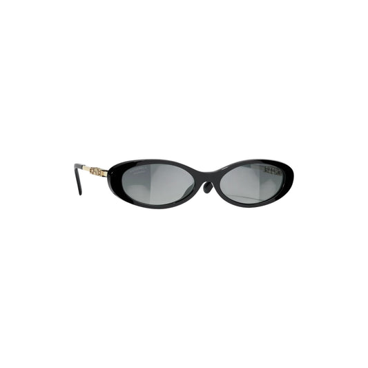 Via Manzoni Boutique Chanel oval sunglasses featuring a black acetate frame and gold-tone logo temples.