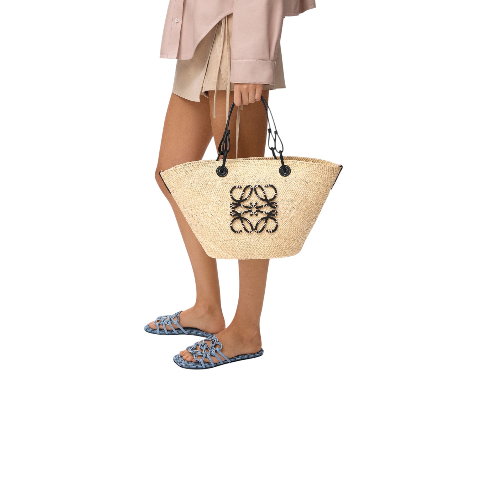 Via Manzoni Boutique model carrying a LOEWE Anagram medium basket bag in natural iraca palm with black calfskin trim.