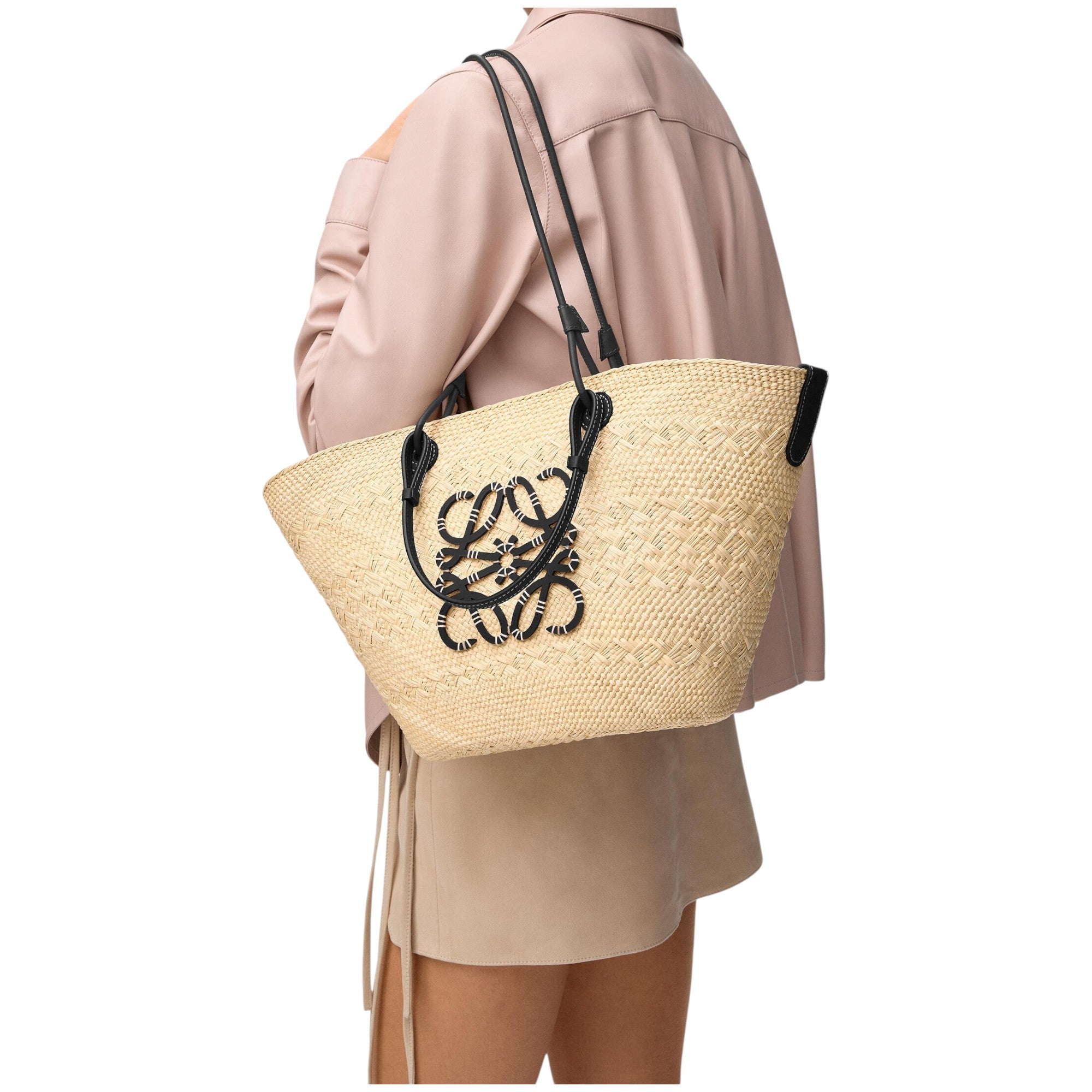 Via Manzoni Boutique model carrying a LOEWE Anagram medium basket bag in natural iraca palm with black calfskin trim.