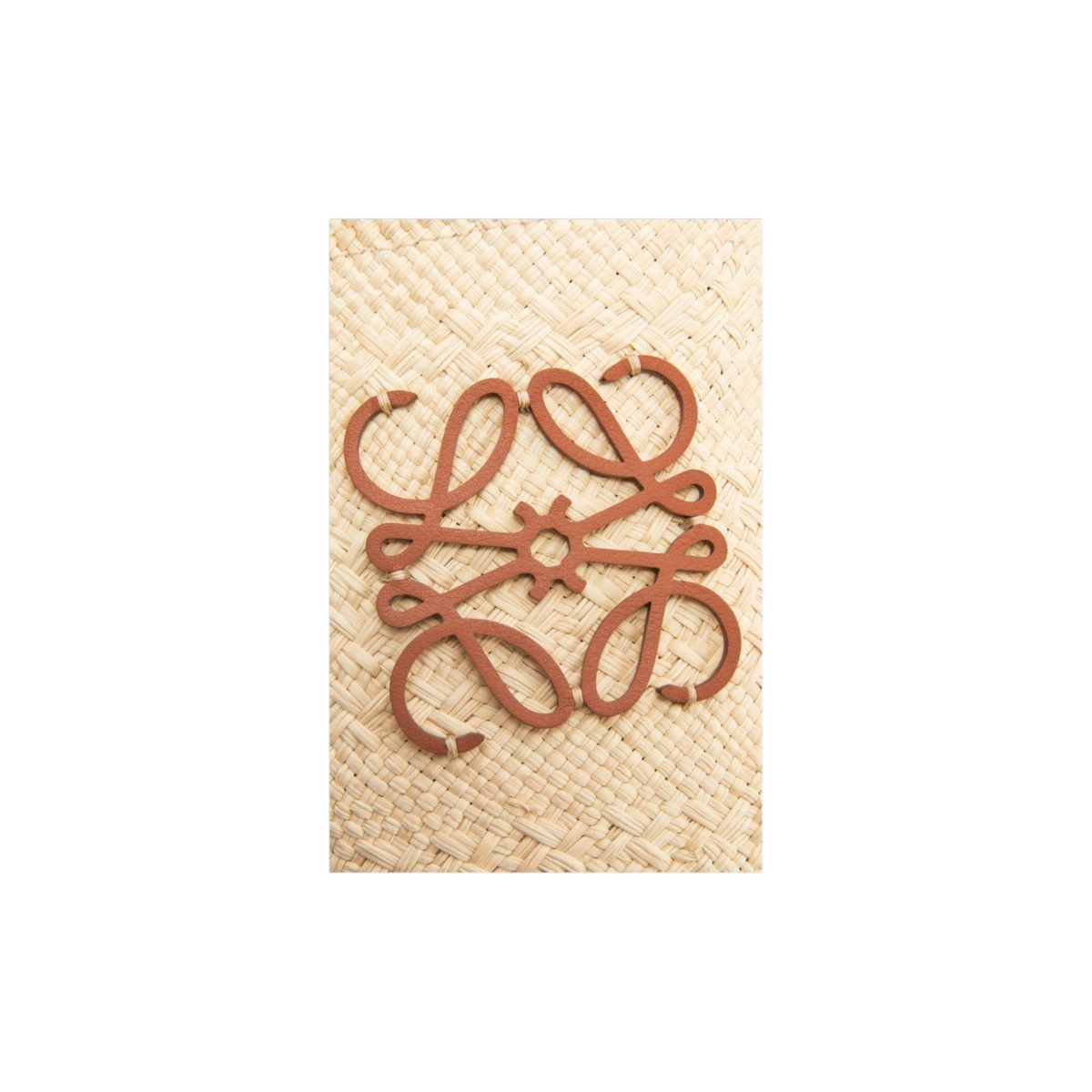 Via Manzoni Boutique LOEWE raffia bag featuring a tan leather Anagram logo patch on a natural woven straw background.